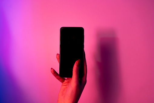 smart phone in female hands on a neon background
