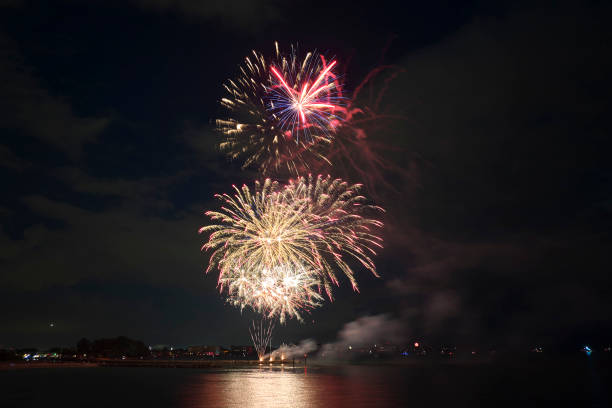 istock Aerial view of bright fireworks exploding with colorful lights over sea shore on US Independence day holiday 1450419256