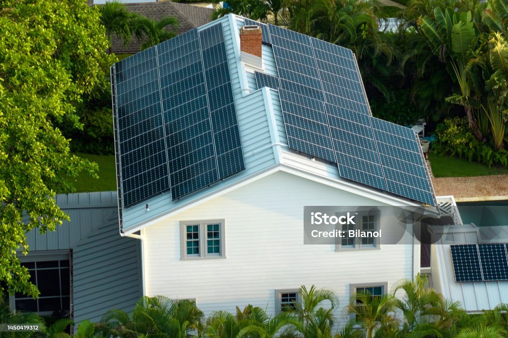 New residential house in USA with roof covered with solar panels for producing of clean ecological electricity in suburban rural area. Concept of investing in autonomous home for energy saving New residential house in USA with roof covered with solar panels for producing of clean ecological electricity in suburban rural area. Concept of investing in autonomous home for energy saving. Solar Panel Stock Photo