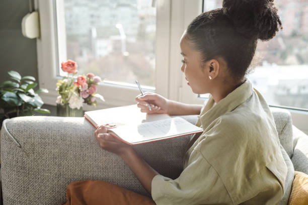 istock Young African American woman writing a diary and thinking 1450420127