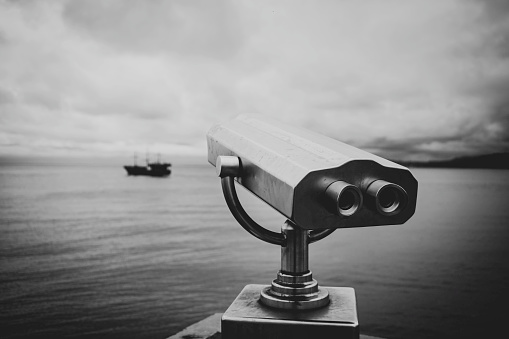 paid observation point for the sea through binoculars, against a blurred background of the sea and a distant ship and sailboat