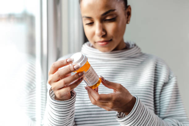 une jeune femme sérieuse tenant un flacon de médicaments - pill bottle photos et images de collection