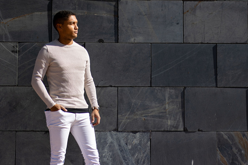 man posing in trousers and a white pullover, horizontal flagstone background