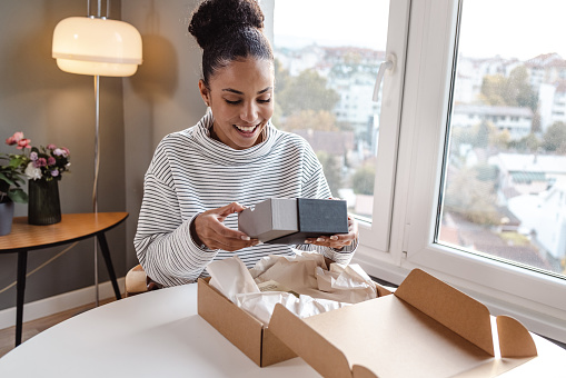 A beautiful woman sitting on the sofa in the living room and unpacking a package