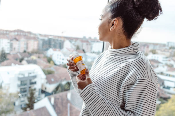 istock A young woman holding a pill bottle abd thinking 1450423016