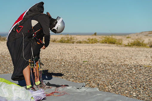 Professional paraglider on flight suit with helmet getting ready for flying. Copy space on right side for text