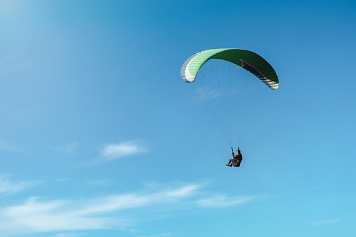 Paraglider flying against the sun on a beautiful sunny day. Copy space on left side