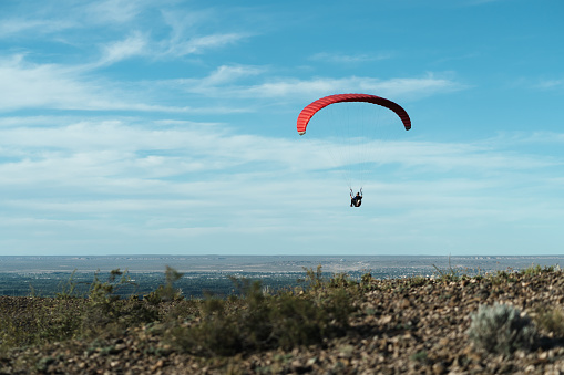Red paragliding take offs on beautiful blue sky with clouds. Copy space for text on left side