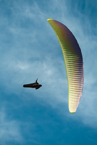 Bottom view of paraglider flying in the cloudy blue sky. Vertical photography. General Roca, Rio Negro, Argentina