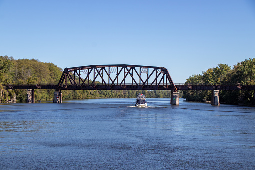 Boats passing under a rusted metal bridge on the Erie Canal