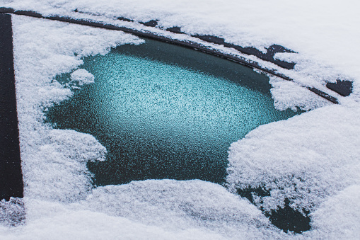 frozen windshield of a car with ice and snow, concept of traffic risks in winter, copy space, selected focus