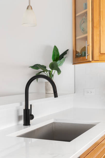 istock A kitchen sink detail with light colored cabinets and a marble countertop. 1450444913