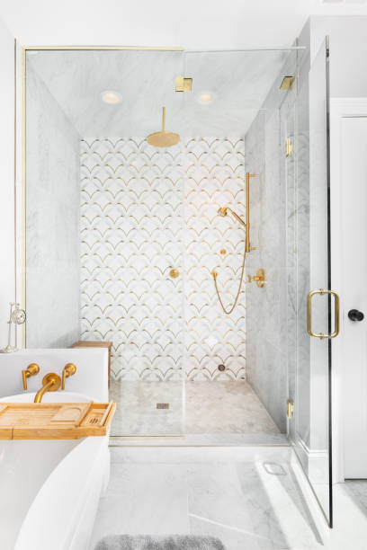 una vasca indipendente e doccia con rubinetti d'oro e una piastrella a mosaico nella doccia. - standalone foto e immagini stock