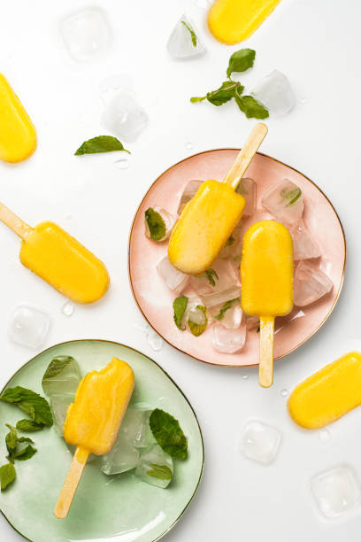 istock Mango popsicles surrounded by min and ice. Mango ice-cream on white background. 1450444999