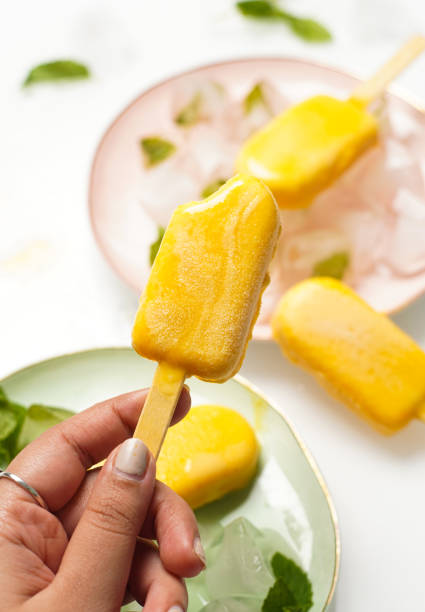 istock Mango popsicles surrounded by min and ice. Mango ice-cream on white background. 1450445000