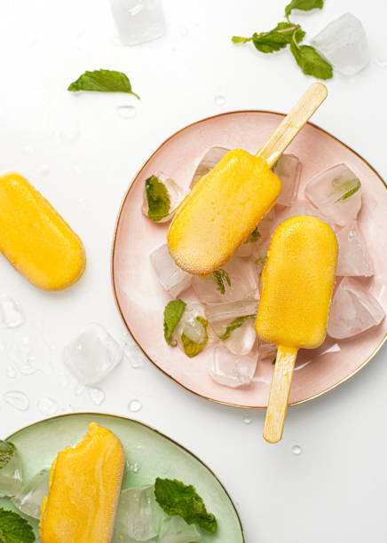Mango popsicles surrounded by min and ice. Mango ice-cream on white background.