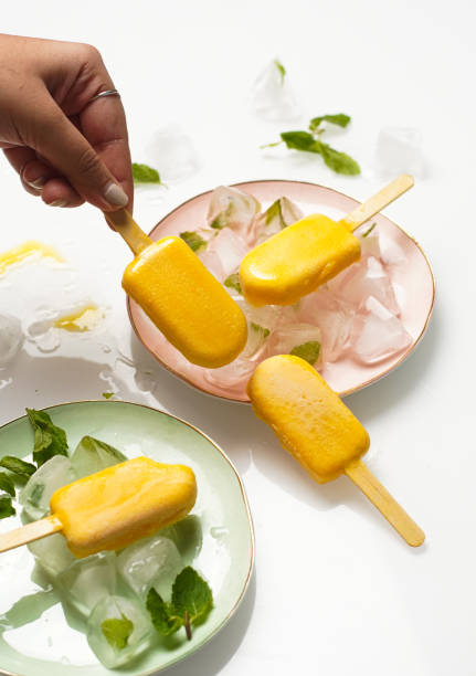 istock Mango popsicles surrounded by min and ice. Mango ice-cream on white background. 1450445005