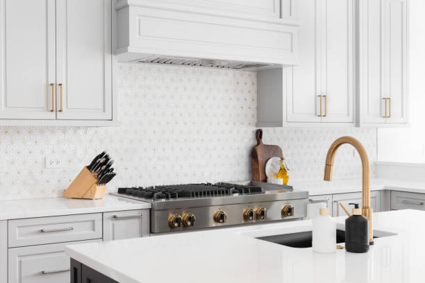 istock A kitchen detail with a gold faucet, grey cabinets, and tiled backsplash. 1450445862