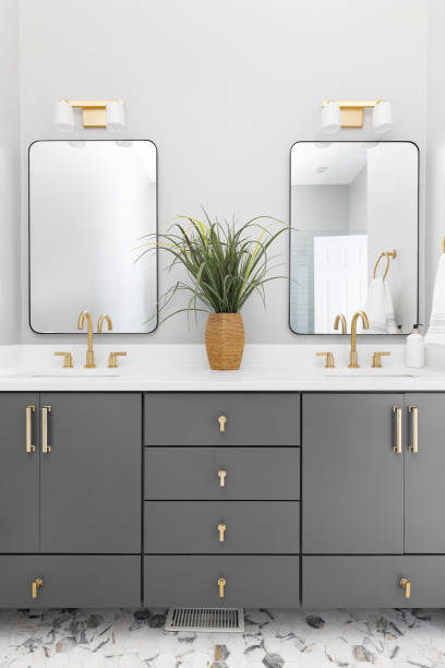 istock A bathroom with a grey cabinet, tiled floors, and gold faucets. 1450445921