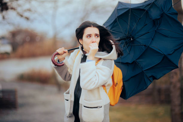 istock Woman Holding Her Umbrella Walking into a Windstorm 1450448997