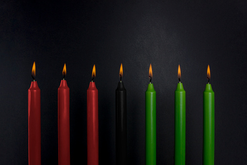 Kwanzaa holiday background. Seven candle light on black background. Afro-American holiday concept. Copy space.