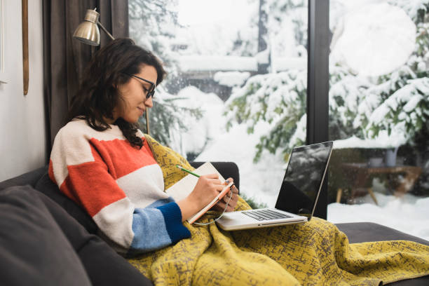 Young woman studying for the exam and warming under the blanket