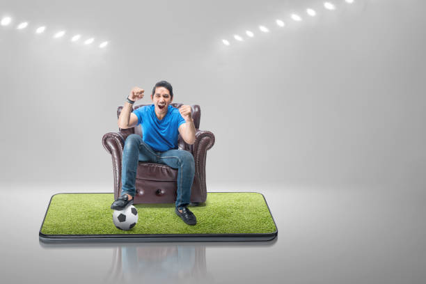 istock Asian man with the ball sitting on the couch with an excited expression 1450465460