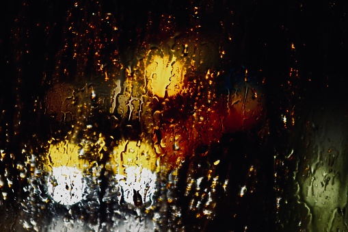 Rain on the window with red and yellow bokeh lights