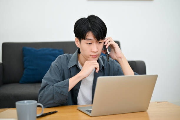 istock Confused man looking at laptop screen while asking a question over the phone call with a coworker 1450513835