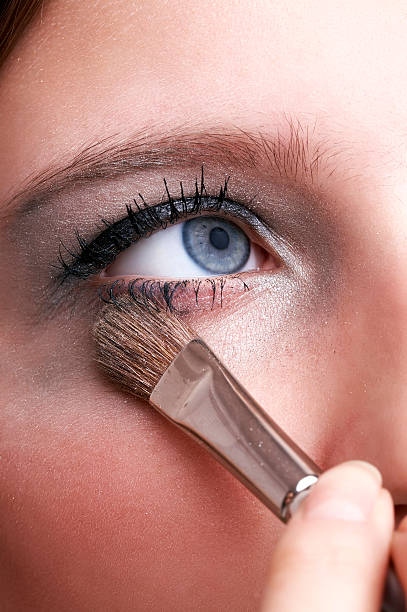 makeup artist applying blue eye powder with brush stock photo