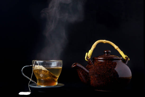 istock steaming tea cup with teapot and black background 1450518966