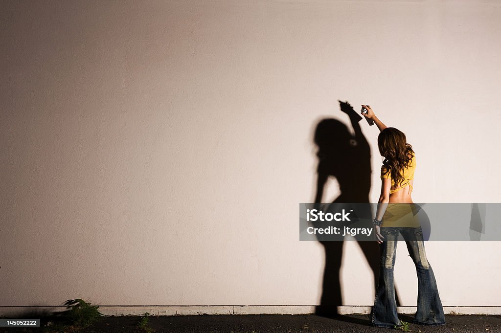 female graffiti artist with copyspace sexy female about to tag a wall with hard dramatic lighting creating a dark shadow Art Stock Photo