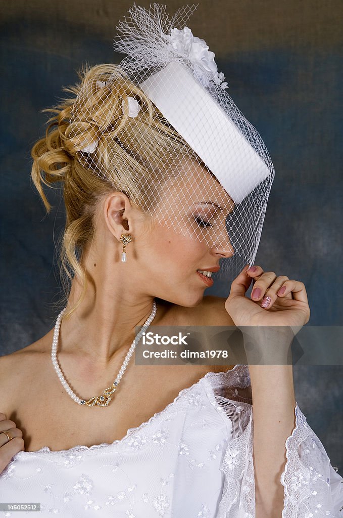 blonde Portrait of the smiling blonde in white wedding dress and hat with veil. Studio photo Adult Stock Photo