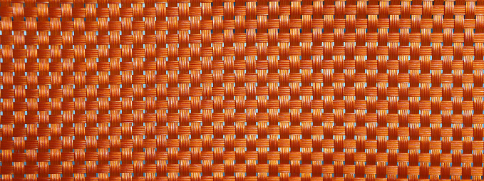 Close up of orange plastic wickerwork. The wickerwork is used for garden furniture. Copy space for your design. Web banner.