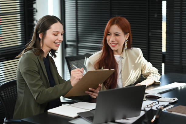 istock Smiling business colleagues talking and examining financial reports at modern workplace. 1450533308