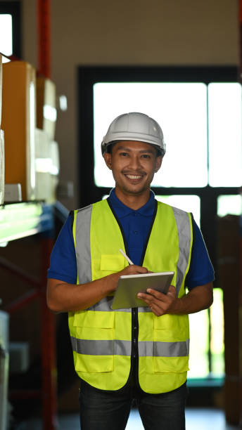 istock Image of man warehouse worker wearing hard hats and reflective jackets using digital tablet in retail warehouse. 1450533400