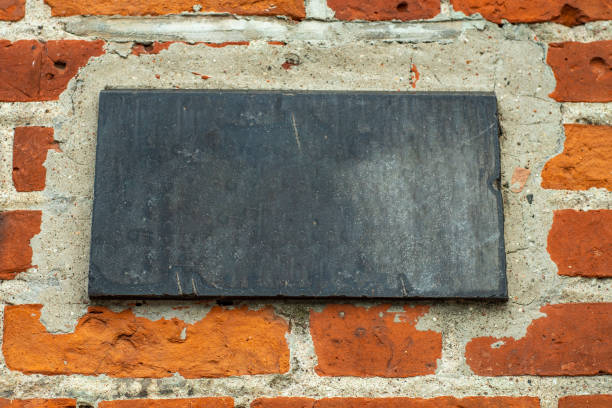 istock An empty, black stone tablet on a brick wall. Template with a dark sign without inscriptions. 1450538354