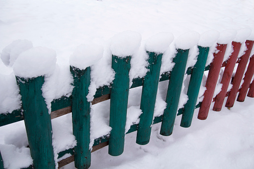 snow on a wooden fence as a background image. Winter at countryside with a snowy old wooden fence, surrounded by a thick layer of snow. Rustic color wooden fence covered with snow