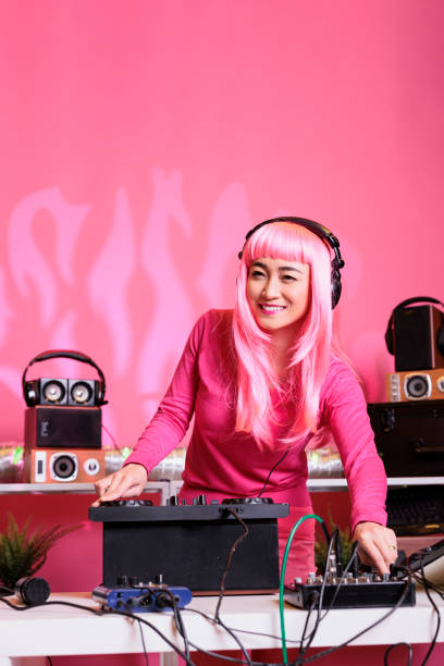 Musician performer playing electronic song using professional turntables at night in club, enjoying performing music with fans. Artist with pink hair doing performance with audio equipment