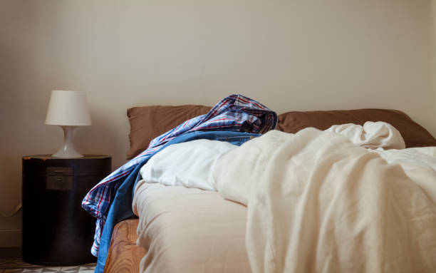 Unwashed clothes on bed in bedroom