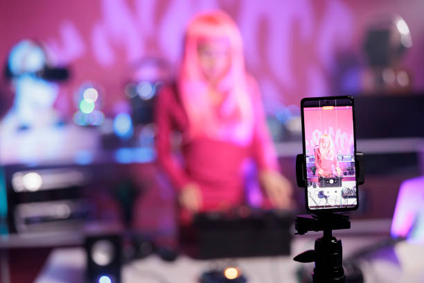 istock Artist with pink hair mixing song at professional turntables having fun while playing techno song in club 1450548837