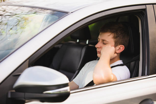 istock Nearly sleeping yound driver being tired waiting in the traffic jam after work in the rush hour. Exhausted young guy stop driving his car for resting. 1450558061