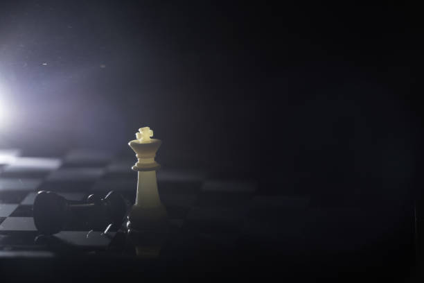istock chess pieces on a chessboard in a dark room illuminated by a lamp 1450560537