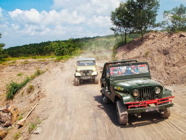 Mount Merapi, Indonesia - Aug 2013: Jeep lava tour off road adventure with hill and mountain in background. Cloudy and sunny blue sky.