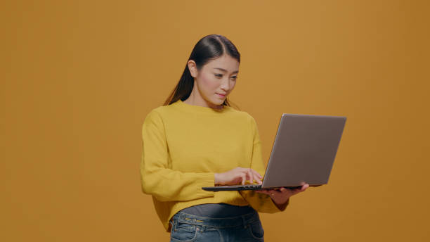 istock Young adult typing on laptop pc with technology in studio 1450565004