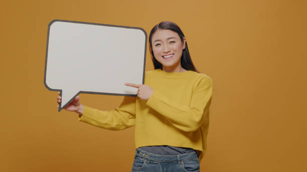 istock Cheerful woman pointing at empty speech bubble in studio 1450565855