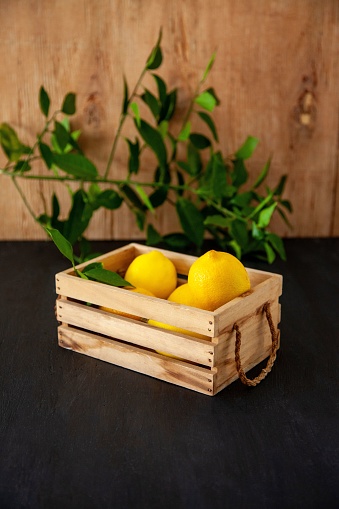A vertical shot of a bunch of lemons in a wooden basket