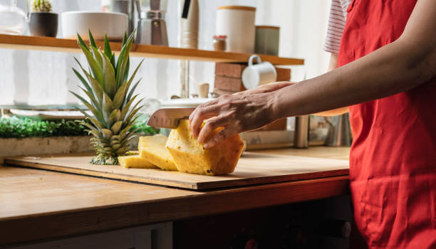istock woman's hand cutting pineapple in the kitchen, using tropical fruit for fresh juice. 1450575889