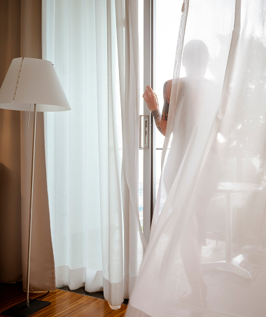 Woman in a black dress in a bright sparse hotel room with big windows