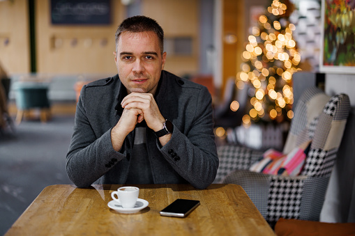 Portrait of handsome man sitting at cafe and looking at camera